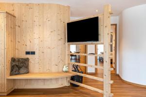 een kamer met een houten muur en een flatscreen-tv bij Les Ciases Chalets Dolomites Apt 2 in San Vigilio Di Marebbe