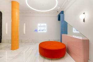 eine orangefarbene Ottomane in einem Zimmer mit Säulen in der Unterkunft Ikonik Gran Vía in Madrid