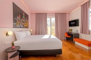 ein Hotelzimmer mit einem großen Bett und einem Schreibtisch in der Unterkunft Ikonik Gran Vía in Madrid