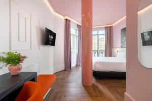 ein Hotelzimmer mit einem Bett und orangefarbenen Stühlen in der Unterkunft Ikonik Gran Vía in Madrid