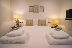 a white bedroom with a large white bed with two chairs at The Muse at Framlingham Sleeps 4 in Framlingham