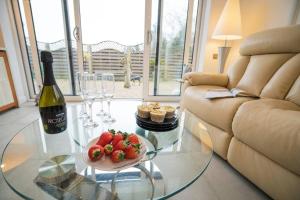 uma sala de estar com uma mesa de vidro com uma garrafa de vinho e morangos em The Muse at Framlingham Sleeps 4 em Framlingham