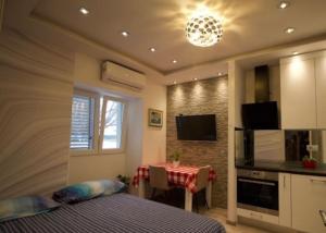 a bedroom with a bed and a table and a kitchen at Mitella studio apartman in Solin