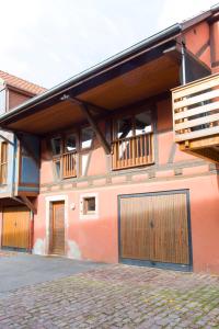 a building with two garage doors and wooden balconies at La couronne Maison 80m2 garage & terrasse in Sainte-Croix-en-Plaine