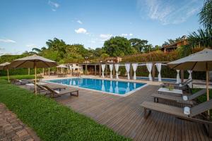 a swimming pool with benches and umbrellas in a yard at Brisa da Serra Pousada Boutique in Tiradentes