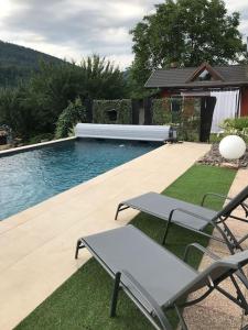 a swimming pool with two chairs and a table at Gîte des Renards in La Broque
