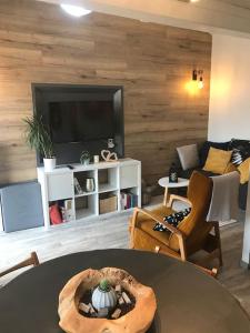 a living room with a table and a couch and a tv at Gîte des Renards in La Broque