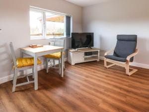 uma sala de estar com uma mesa e duas cadeiras e uma televisão em Meols Holiday Lodge em Wirral
