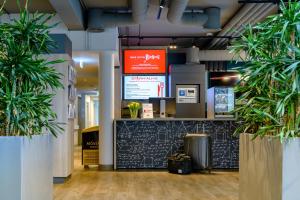 a lobby with two potted plants and a counter at ibis Köln Frechen in Cologne
