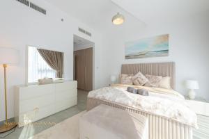 a white bedroom with a large bed and a window at Marco Polo - Stunning 2 BR With Marina Views, Huge Pool & Gym in Dubai