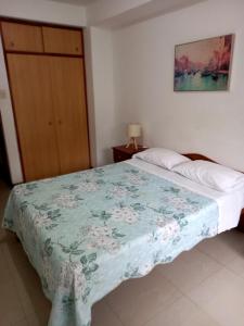 a bedroom with a bed with a blue and white blanket at Bellos Dptos Huanchaco, Perú a 50 metros del mar in Trujillo