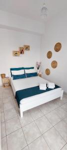 a white bedroom with a large bed with blue pillows at Kato Yialos Paros in Parikia