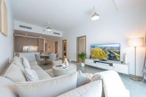 a living room with a white couch and a tv at Marco Polo - Stunning 2 BR With Marina Views, Huge Pool & Gym in Dubai