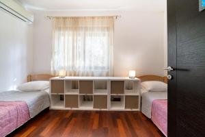 a bedroom with two beds and a table with two lamps at Ladybug in Dobrota