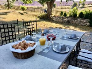 - une table de pique-nique avec un panier de pain et du jus d'orange dans l'établissement Domaine La Lauren avec piscine chauffée et jacuzzi, à Ferrassières