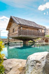 a wooden building on a bridge over a river at Glamping Alliance Hotel in Plovdiv
