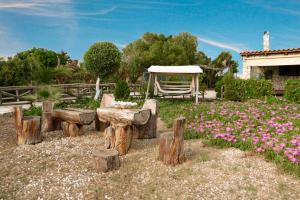 een tuin met houtblokken en een prieel en bloemen bij Beachhouse Kokkinos Pyrgos in Kókkinos Pírgos