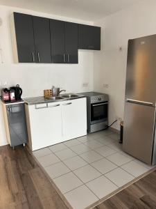 een keuken met witte kasten en een roestvrijstalen koelkast bij Appartement 2 pièces ligne 1 in Montreuil