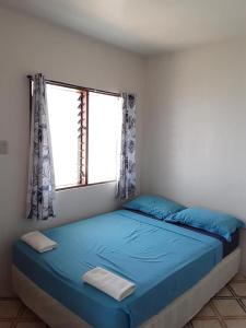 a bedroom with a blue bed and a window at Islanders Paradise Beach in Larena