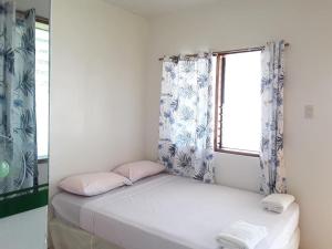 a small bed in a room with a window at Islanders Paradise Beach in Larena
