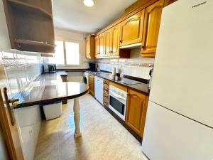 a kitchen with wooden cabinets and a white refrigerator at Bonito piso 2 bed 2 bath El Drac in El Campello