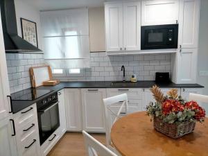 una cocina con armarios blancos y una mesa con flores. en Piso con encanto en pleno centro, en Oviedo 8 fotos más