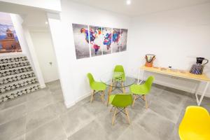 a dining room with green chairs and a glass table at Hospedería El Alarife in Úbeda