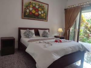 - une chambre avec 2 lits et un tableau mural dans l'établissement Nyoman Homestay Ubud, à Ubud