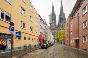 eine Stadtstraße mit Gebäuden und einer Kathedrale im Hintergrund in der Unterkunft a&o Köln Dom in Köln