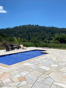 a patio with a blue pool and a bench at pousada vila das oliveiras in Pirenópolis
