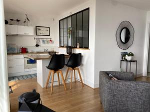 a kitchen and living room with a counter and stools at Splendide vue face à la mer avec garage in Concarneau