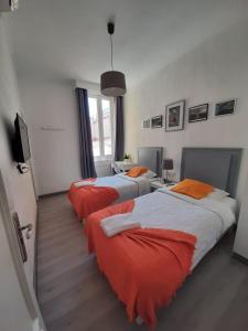 a bedroom with two beds with orange and white sheets at CH Lumiere in Madrid