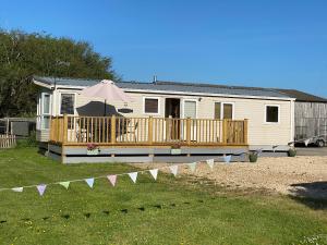 a mobile home with a deck and an umbrella at The Hideaway in Weymouth