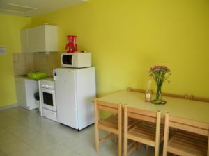 a kitchen with a small table and a white refrigerator at Gîtes de La Futaie in Sauzé-Vaussais