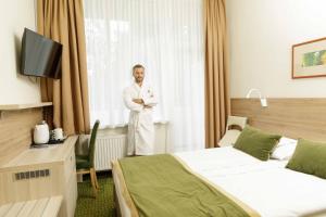 Un homme debout dans une chambre d'hôtel avec ses bras croisés dans l'établissement Medical SPA "Eglės sanatorija" Standard Druskininkai, à Druskininkai