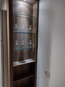 um armário de madeira com prateleiras de vidro num quarto em Apartamento no coração de Poços de Caldas em Poços de Caldas