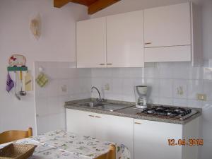 ブレンゾーネにあるAppartamento Lauraの白いキャビネット、シンク、テーブル付きのキッチンが備わります。
