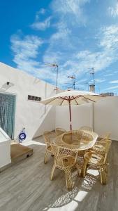 Un patio con una mesa y sillas y una sombrilla. en Casa Pichusa, en Benicarló