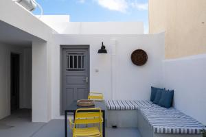 a patio with a bench and two yellow chairs at Villa Tholos & Prive Jacuzzi in Kamari