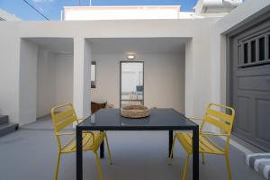 a dining room with a black table and yellow chairs at Villa Tholos & Prive Jacuzzi in Kamari