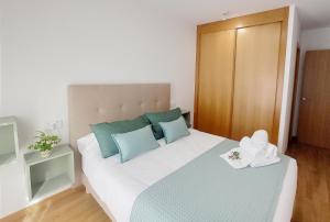 a bedroom with a large bed with blue and green pillows at Aronda Cambados apartamento céntrico in Cambados