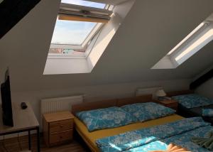 een slaapkamer op zolder met 2 bedden en een dakraam bij Pension Sara in Hevlín