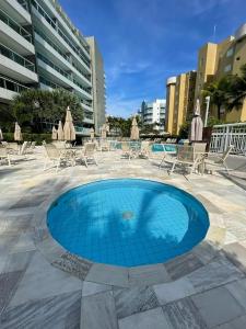 a swimming pool with chairs and tables and umbrellas at Ilha da Madeira Resort Riviera de São Lourenço SP in Bertioga