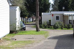 una casa y un coche estacionados al lado de una calle en Location 221 Mobil home gamme elegance aux Dunes de Contis 3 without Fun Pass, en Saint-Julien-en-Born