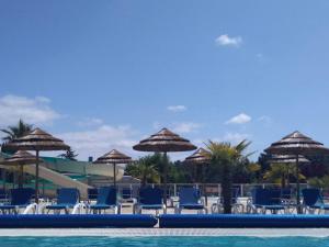 una piscina con sillas y sombrillas azules en Location 221 Mobil home gamme elegance aux Dunes de Contis 3 without Fun Pass, en Saint-Julien-en-Born