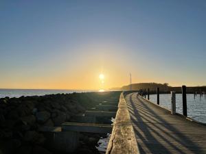 um cais com o pôr do sol sobre a água em Vogelnest em Grömitz