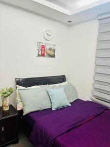 a bedroom with a bed with purple sheets and a clock on the wall at ADB Tower 1 bedroom with fast wifi and Netflix at Ortigas across Robinson's Galleria in Manila