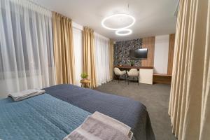 um quarto de hotel com uma cama azul e uma secretária em Hotel Zemplín em Trebišov