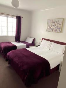 two beds in a hotel room with purple sheets at Green Acre Motel in North Cornelly