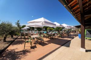 un patio esterno con tavoli, sedie e ombrelloni di Camping les Cigales Rocamadour a Rocamadour